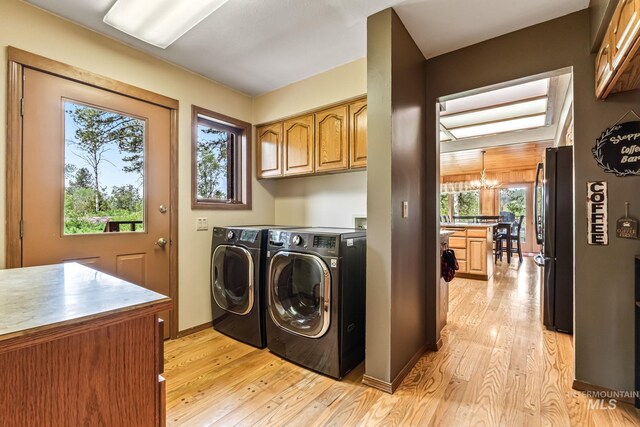 14060 Deerfield, Mccall, ID 83638 - laundry room with cabinet space, separate washer and dryer, light wood-style floors, a chandelier, and baseboards