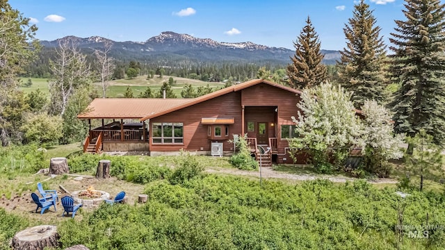 14060 Deerfield, Mccall, ID 83638 - rear view of house with a fire pit, a deck with mountain view, metal roof, and a wooded view
