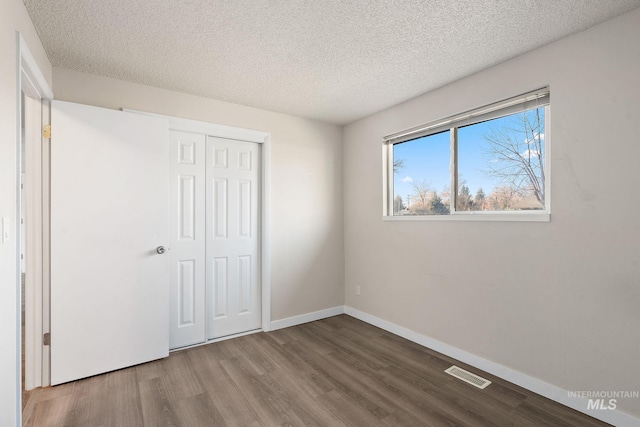 unfurnished bedroom with hardwood / wood-style floors, a textured ceiling, and a closet