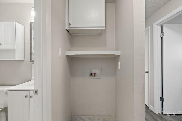 clothes washing area featuring hookup for a washing machine and a textured ceiling