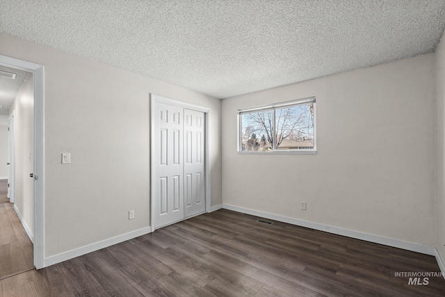 unfurnished bedroom with a closet, a textured ceiling, and dark hardwood / wood-style floors