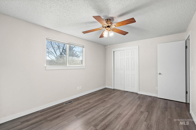 unfurnished bedroom featuring ceiling fan, a textured ceiling, dark hardwood / wood-style floors, and a closet