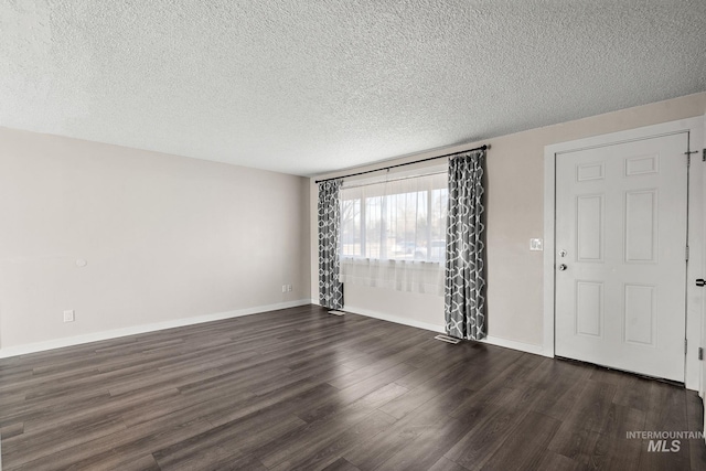 spare room featuring dark hardwood / wood-style floors and a textured ceiling