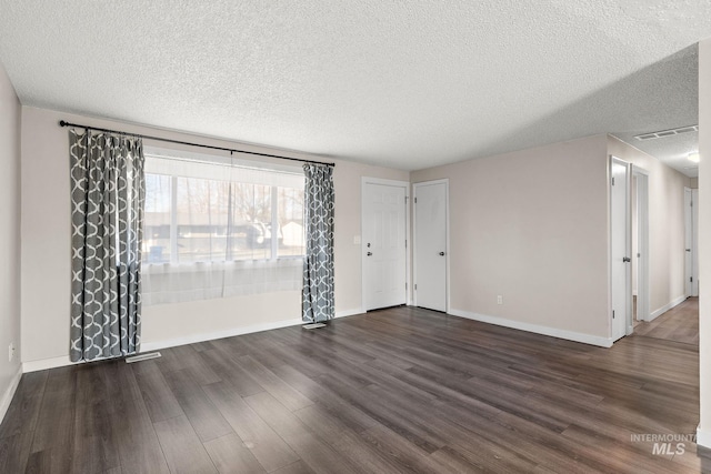 empty room featuring a textured ceiling and dark hardwood / wood-style flooring