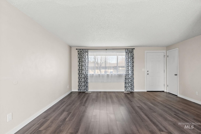 empty room featuring dark wood-type flooring and a textured ceiling