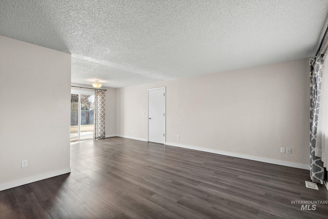 empty room featuring a textured ceiling and dark hardwood / wood-style floors