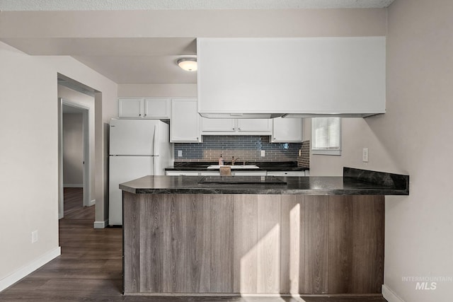 kitchen featuring kitchen peninsula, white cabinets, decorative backsplash, and white fridge