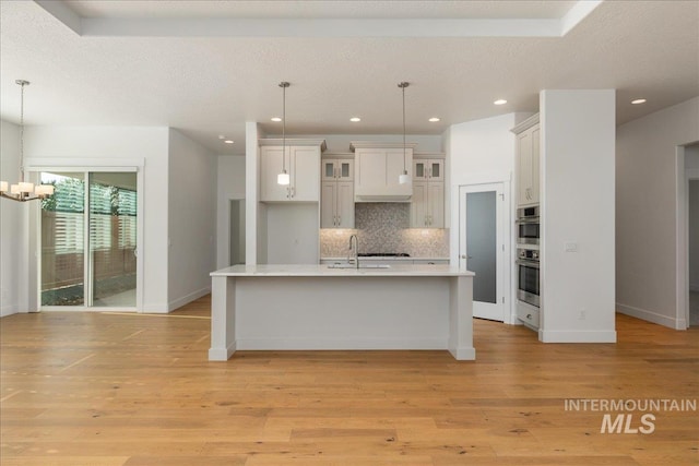 kitchen featuring light hardwood / wood-style flooring, pendant lighting, a chandelier, and tasteful backsplash