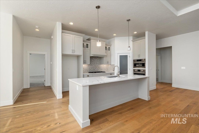 kitchen featuring light hardwood / wood-style floors, white cabinetry, sink, stainless steel double oven, and light stone counters