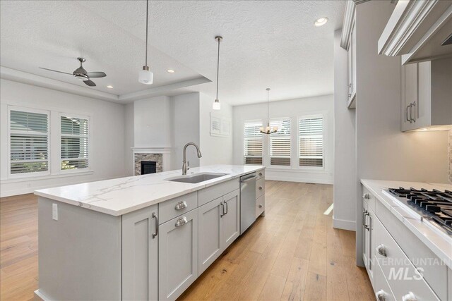 kitchen featuring light hardwood / wood-style flooring, a wealth of natural light, sink, a fireplace, and a center island with sink