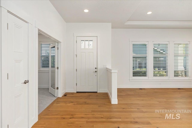 carpeted entrance foyer featuring a raised ceiling and plenty of natural light