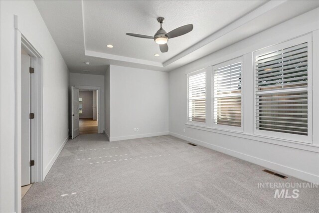 carpeted spare room featuring ceiling fan, a raised ceiling, and a textured ceiling