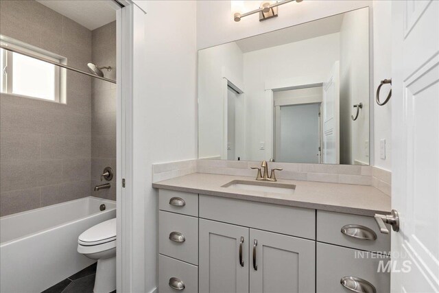 full bathroom with toilet, tiled shower / bath combo, vanity, and tile patterned floors