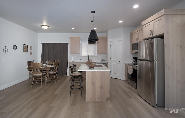 1635 Trail Way, Weiser, ID 83672 - kitchen featuring stainless steel appliances, a kitchen breakfast bar, light brown cabinets, light countertops, and light wood finished floors