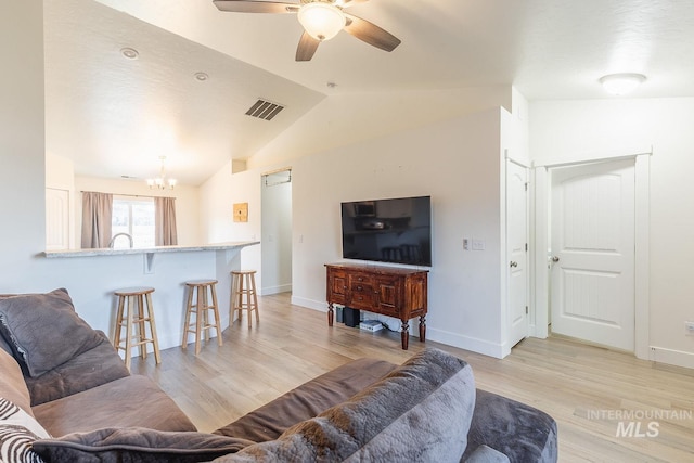 living room with light wood-type flooring, lofted ceiling, and ceiling fan with notable chandelier