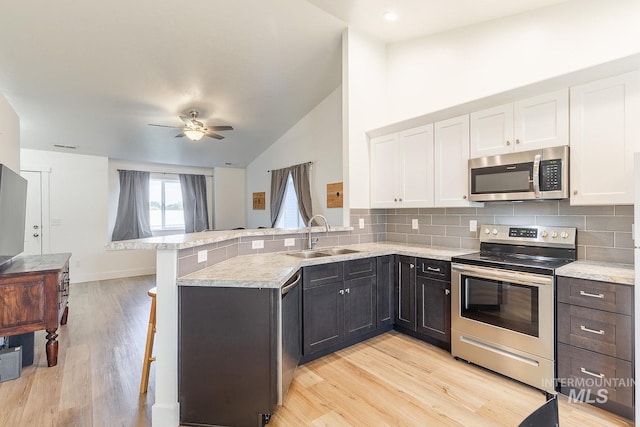 kitchen featuring white cabinets, a kitchen bar, stainless steel appliances, sink, and kitchen peninsula