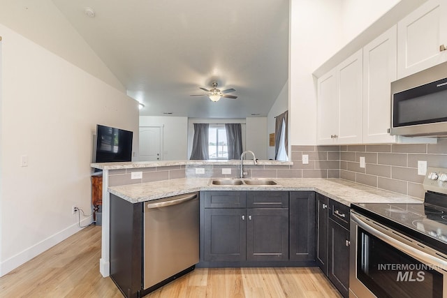 kitchen with tasteful backsplash, kitchen peninsula, sink, stainless steel appliances, and white cabinets