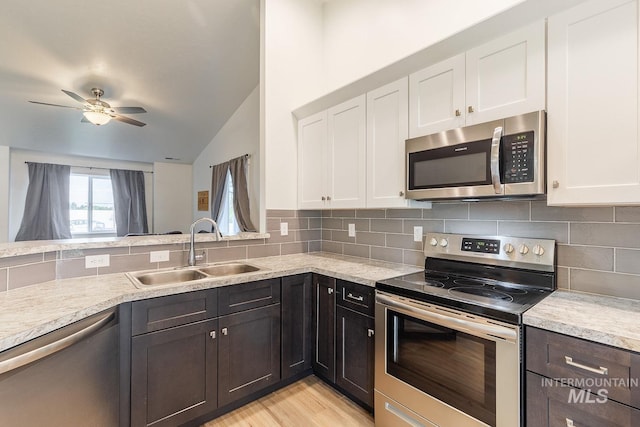 kitchen with stainless steel appliances, white cabinets, tasteful backsplash, and sink