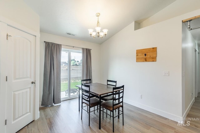 dining area featuring light hardwood / wood-style flooring, a chandelier, and vaulted ceiling