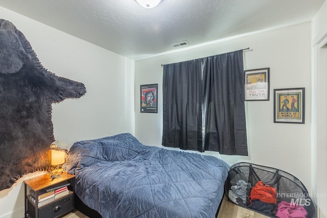 bedroom with a textured ceiling and hardwood / wood-style floors