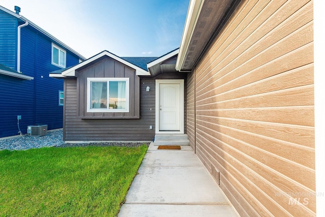 entrance to property with a lawn and cooling unit