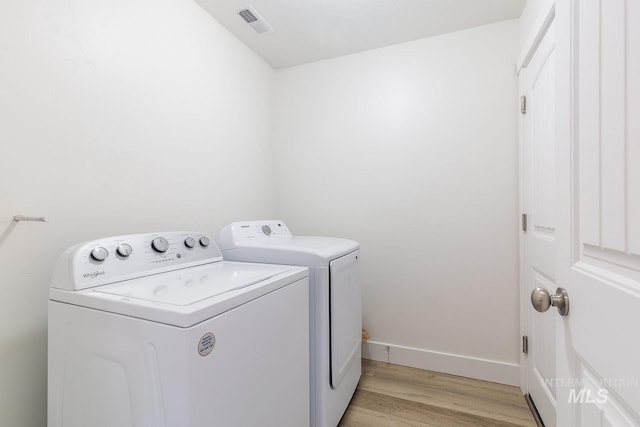 laundry area with washer and dryer and light hardwood / wood-style floors