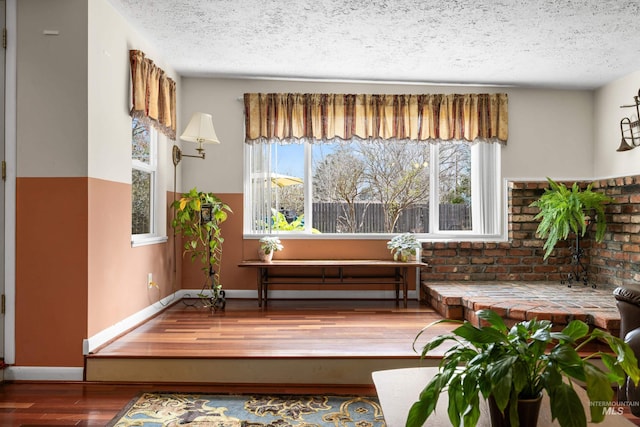 sitting room featuring wood finished floors, baseboards, and a textured ceiling