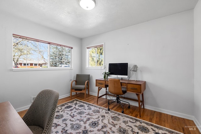 office space featuring baseboards, wood finished floors, and a textured ceiling