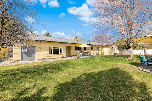back of house featuring a yard, a chimney, fence, and a patio