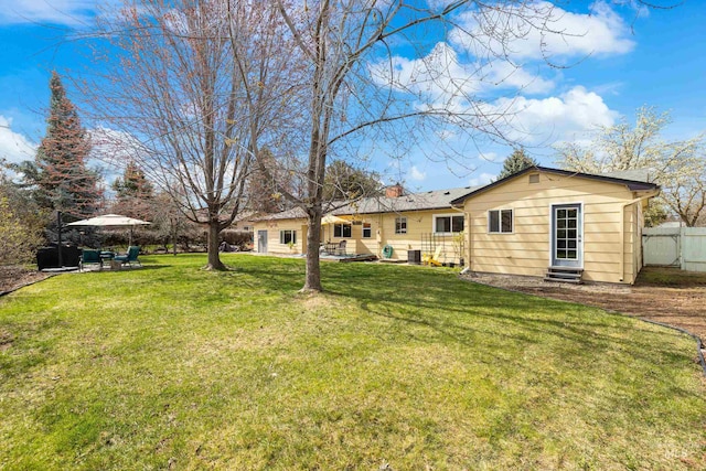 rear view of property featuring fence, entry steps, a patio, central AC, and a yard