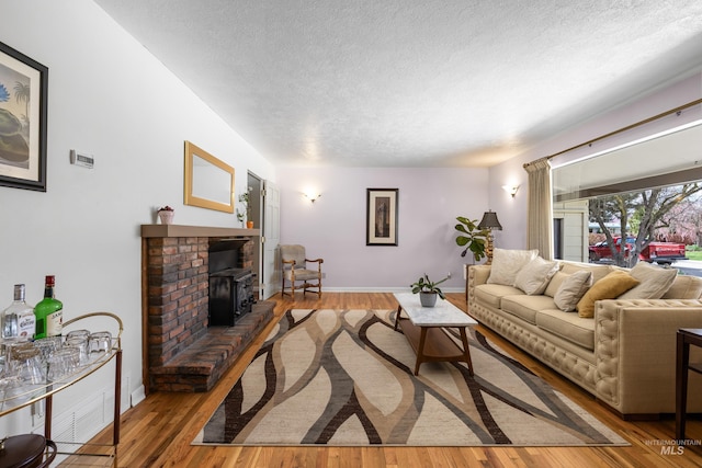 living area with baseboards, a textured ceiling, and wood finished floors
