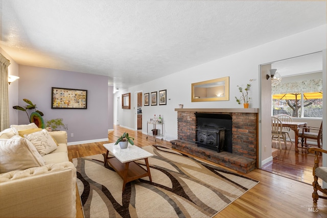 living room featuring baseboards, a textured ceiling, and light wood-style floors