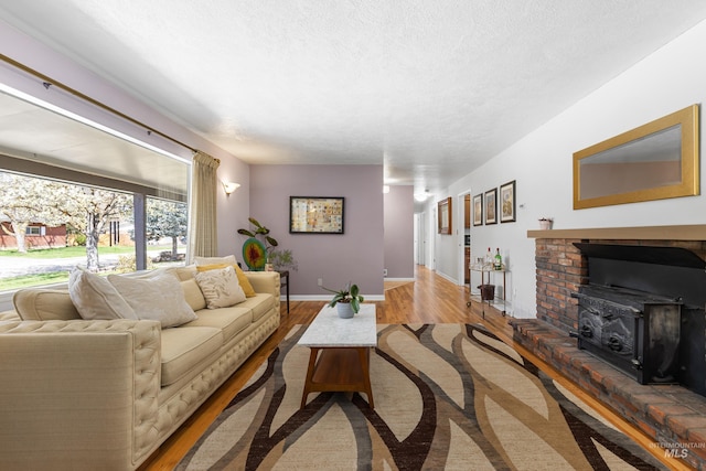 living room with wood finished floors, a textured ceiling, baseboards, and a wood stove