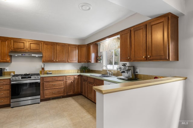 kitchen featuring a sink, under cabinet range hood, gas range, and brown cabinets
