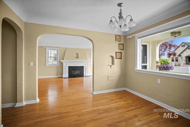 3205 W Crescent Rim Dr, Boise, ID 83706 - unfurnished dining area featuring light wood finished floors, arched walkways, a chandelier, and a textured wall