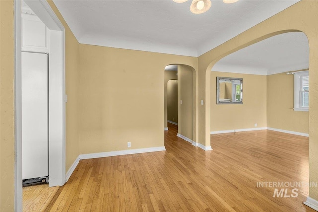 3205 W Crescent Rim Dr, Boise, ID 83706 - empty room featuring arched walkways, light wood-style flooring, and baseboards