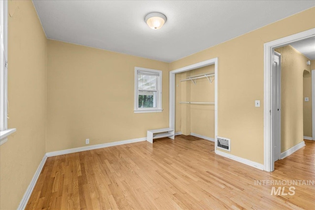3205 W Crescent Rim Dr, Boise, ID 83706 - unfurnished bedroom with light wood-style floors, a closet, baseboards, and arched walkways
