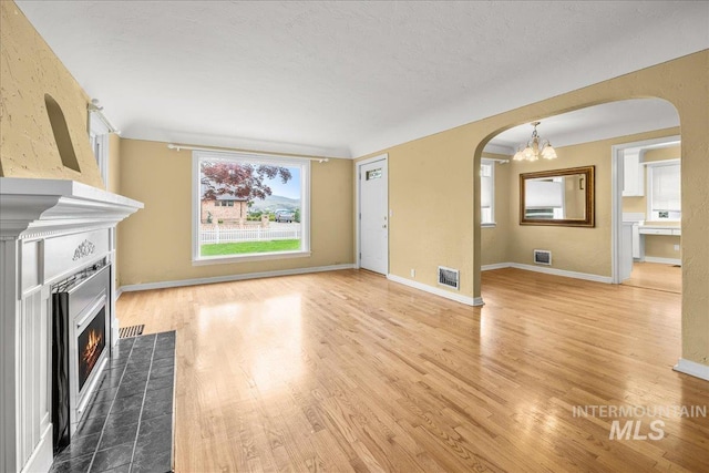3205 W Crescent Rim Dr, Boise, ID 83706 - unfurnished living room featuring arched walkways, wood finished floors, a lit fireplace, and baseboards