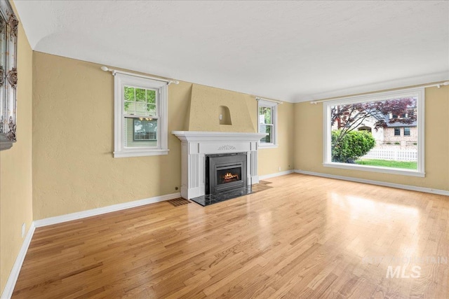 3205 W Crescent Rim Dr, Boise, ID 83706 - unfurnished living room featuring wood finished floors, a fireplace with flush hearth, baseboards, and a textured wall