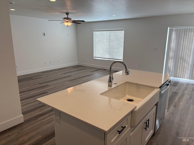 kitchen featuring sink, dark wood-type flooring, a kitchen island with sink, light stone countertops, and white cabinets