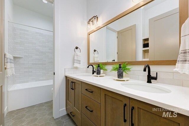 bathroom featuring tile patterned floors, backsplash, vanity, and tiled shower / bath