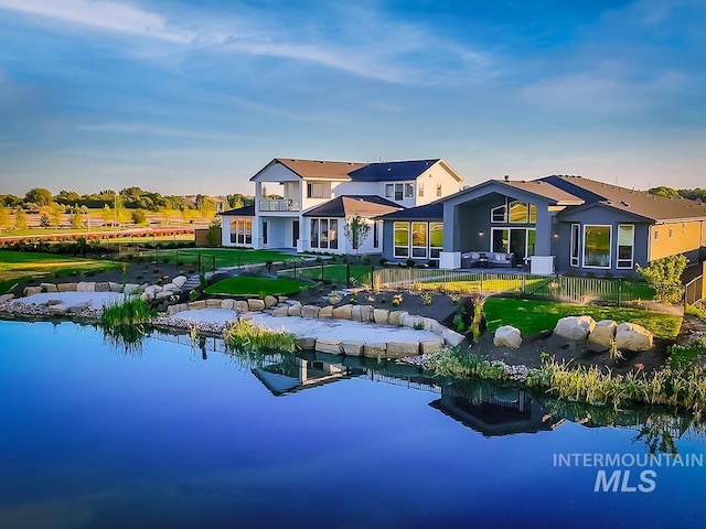 back of property with a water view and a lawn