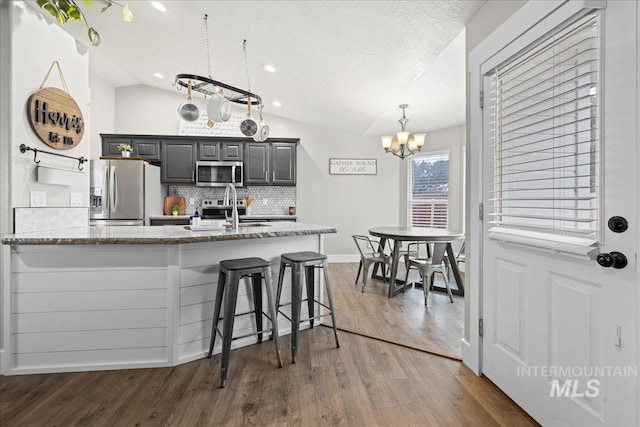 535 Seasons Ct, Nampa, ID 83686 - kitchen featuring appliances with stainless steel finishes, lofted ceiling, a chandelier, decorative backsplash, and dark wood finished floors