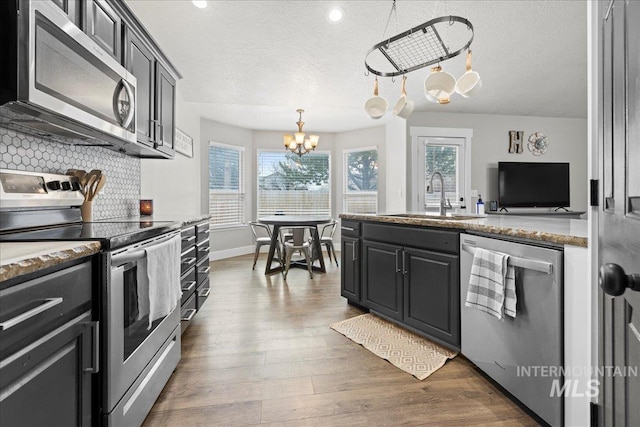535 Seasons Ct, Nampa, ID 83686 - kitchen featuring appliances with stainless steel finishes, a sink, a chandelier, backsplash, and wood finished floors