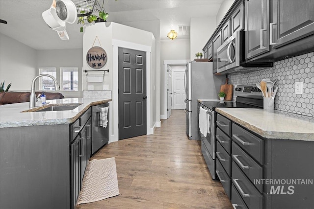 535 Seasons Ct, Nampa, ID 83686 - kitchen featuring a sink, stainless steel appliances, backsplash, light wood-type flooring, and light stone countertops