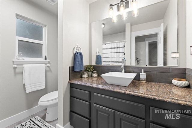535 Seasons Ct, Nampa, ID 83686 - bathroom featuring toilet, tasteful backsplash, vanity, and baseboards