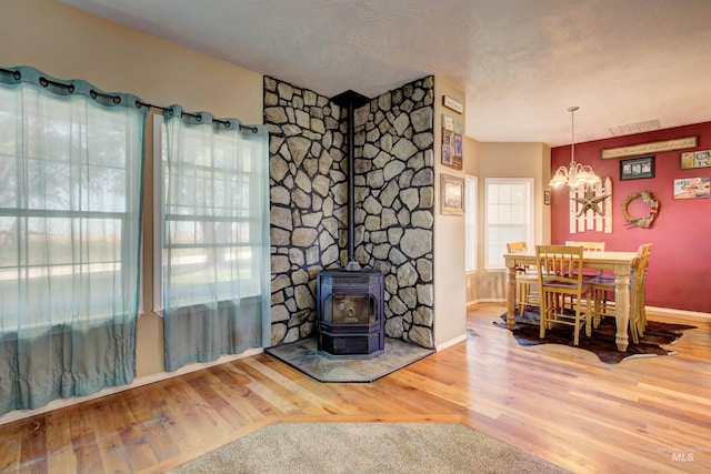 28284 Tudie Ln, Parma, ID 83660 - dining room with an inviting chandelier, wood finished floors, visible vents, a wood stove, and baseboards