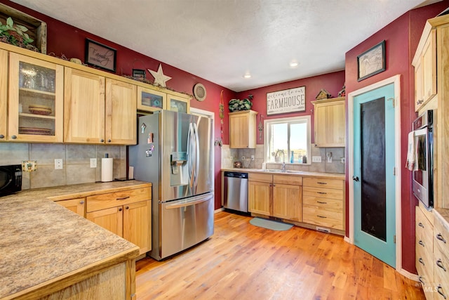 28284 Tudie Ln, Parma, ID 83660 - kitchen with stainless steel appliances, light wood-style flooring, a sink, tasteful backsplash, and light countertops