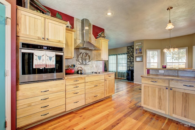 28284 Tudie Ln, Parma, ID 83660 - kitchen with light brown cabinets, light wood-style flooring, stainless steel oven, black electric cooktop, and wall chimney exhaust hood