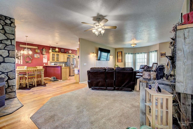28284 Tudie Ln, Parma, ID 83660 - living room featuring ceiling fan with notable chandelier, a textured ceiling, light wood-style floors, and a wood stove
